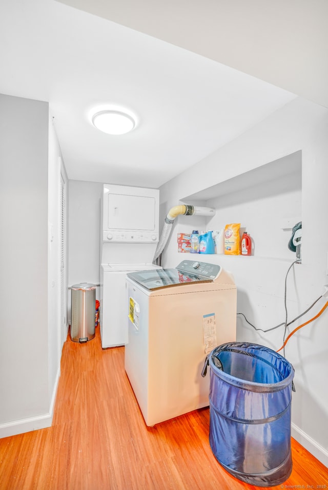 laundry room featuring estacked washer and dryer, light wood-style flooring, and baseboards