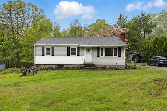 view of front of house featuring a chimney, a front yard, and a shingled roof