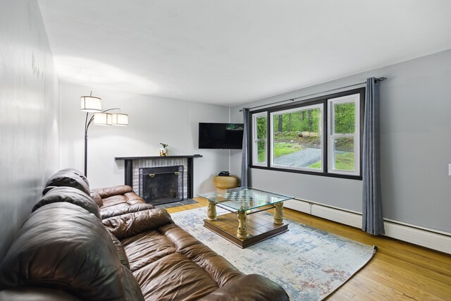 living room with wood finished floors and a brick fireplace