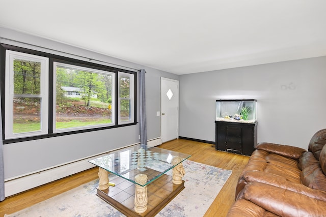 living area featuring light wood-style flooring, a baseboard heating unit, and baseboards