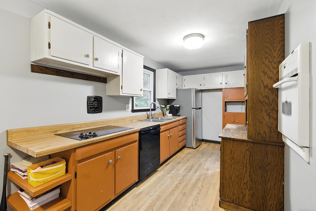 kitchen featuring a sink, black appliances, light wood-type flooring, white cabinetry, and light countertops