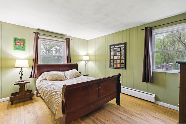 bedroom with baseboard heating, hardwood / wood-style flooring, and baseboards