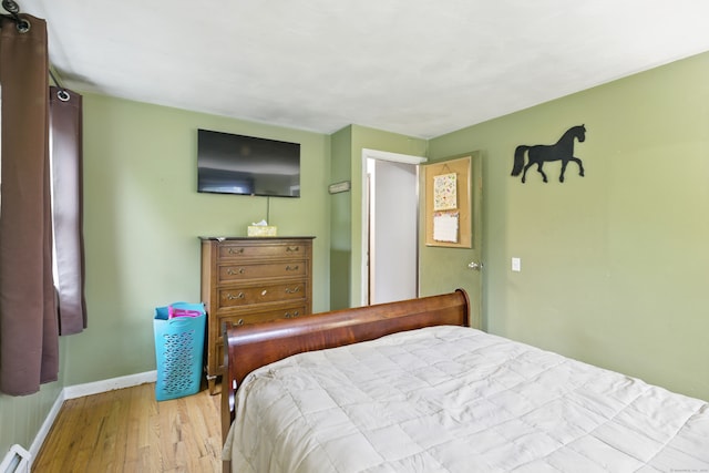 bedroom with wood finished floors, baseboards, and a baseboard radiator