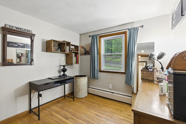office area with baseboard heating, light wood-type flooring, and baseboards