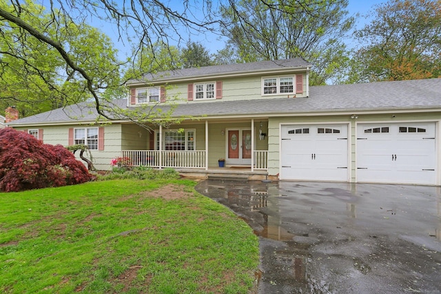 traditional-style home featuring driveway, covered porch, an attached garage, a front lawn, and a shingled roof