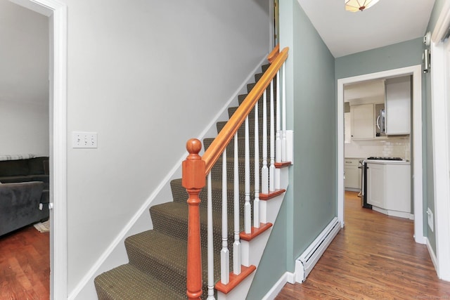 staircase featuring baseboard heating, wood finished floors, and baseboards