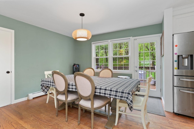 dining space featuring light wood finished floors, baseboard heating, and baseboards