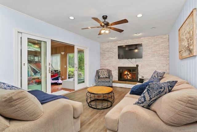 living room featuring wood finished floors, a ceiling fan, a fireplace, french doors, and recessed lighting