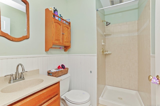 full bathroom with toilet, a stall shower, a wainscoted wall, and vanity