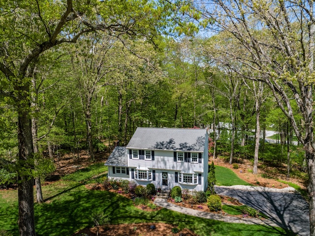 view of front of property featuring a front yard and a view of trees