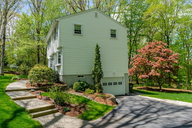 view of side of home featuring an attached garage and asphalt driveway