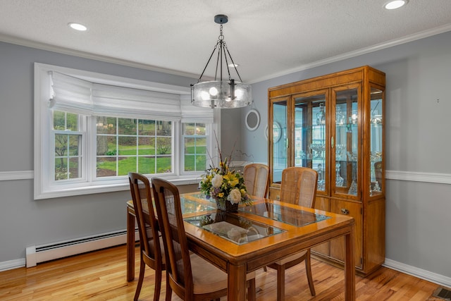 dining space with a chandelier, healthy amount of natural light, a baseboard radiator, light wood-style flooring, and crown molding