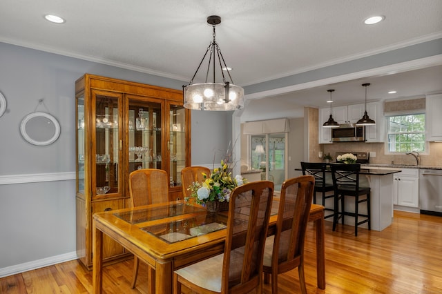 dining room featuring light wood-style floors, a chandelier, recessed lighting, ornamental molding, and baseboards