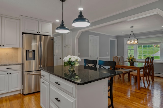 kitchen featuring stainless steel fridge with ice dispenser, light wood finished floors, backsplash, a breakfast bar, and a kitchen island