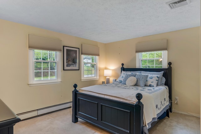 carpeted bedroom featuring baseboard heating, a textured ceiling, and baseboards