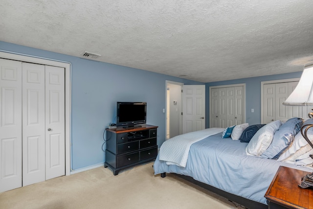 bedroom with two closets, light colored carpet, and baseboards