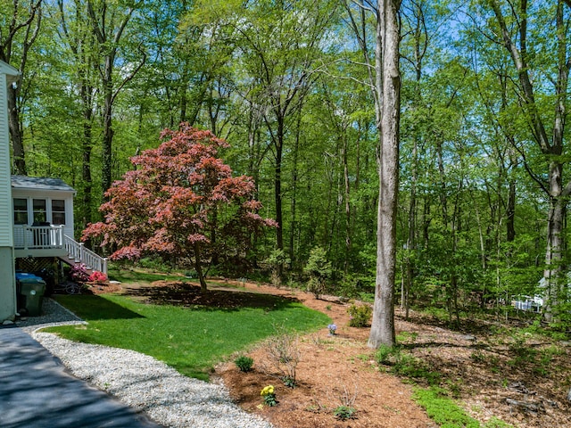 view of grassy yard featuring a forest view and stairway