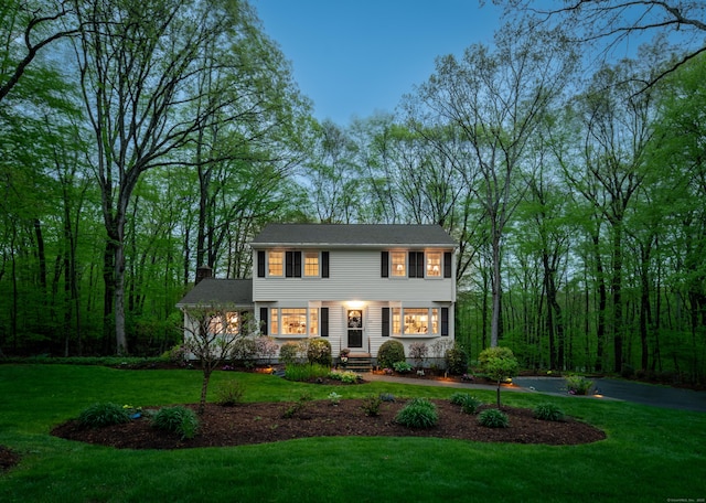 colonial inspired home featuring a chimney and a front lawn
