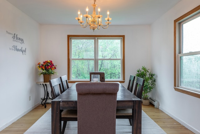dining space featuring a chandelier, baseboard heating, light wood-style floors, and baseboards