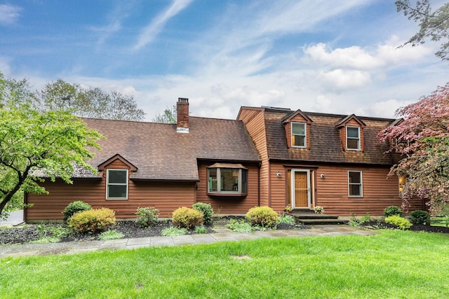 view of front of property featuring a front lawn, roof with shingles, and a chimney