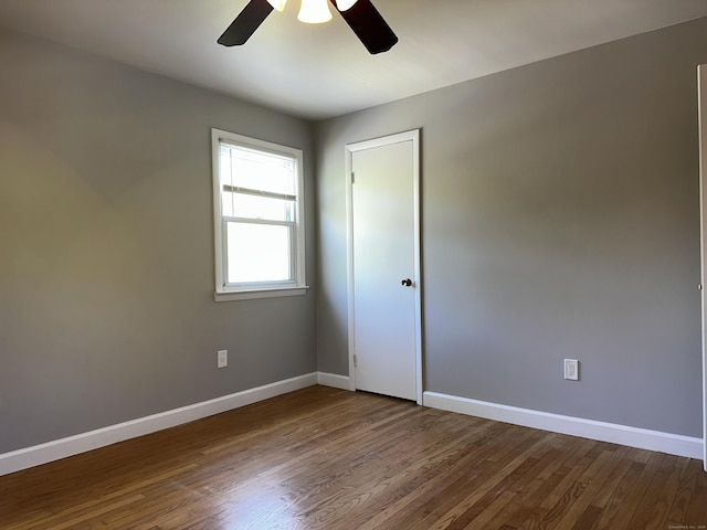 unfurnished room featuring ceiling fan, baseboards, and dark wood-type flooring