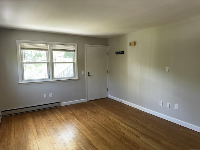 unfurnished room featuring hardwood / wood-style flooring, baseboards, and baseboard heating