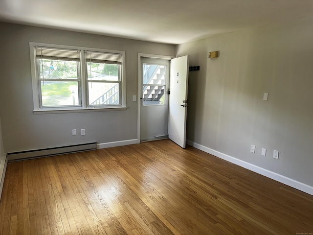 spare room with a baseboard heating unit, hardwood / wood-style flooring, healthy amount of natural light, and baseboards