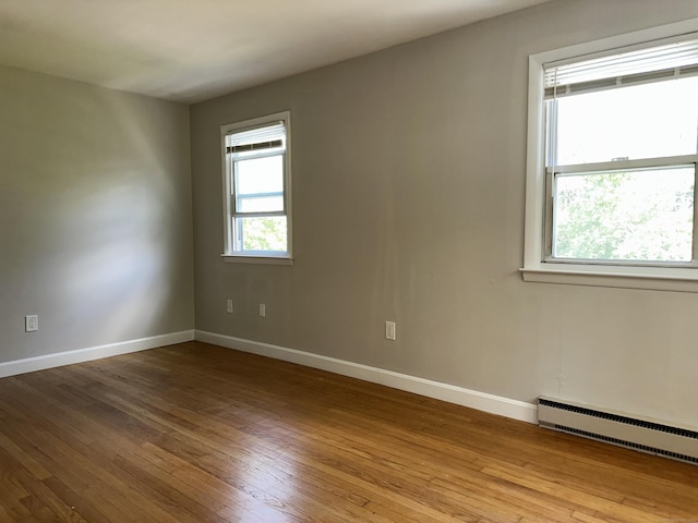 unfurnished room with a baseboard radiator, hardwood / wood-style floors, and baseboards