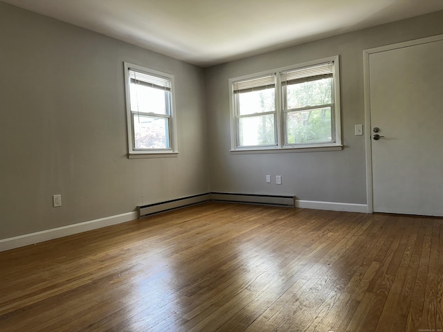 spare room featuring wood-type flooring, baseboards, and a baseboard heating unit
