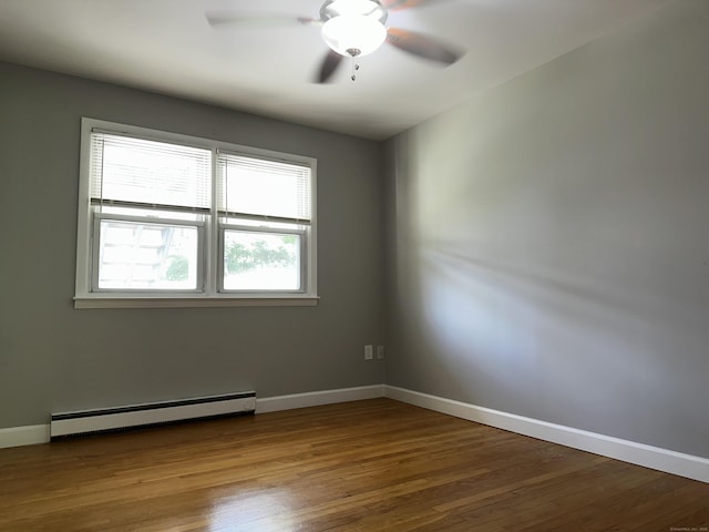 spare room featuring a baseboard radiator, a ceiling fan, wood finished floors, and baseboards