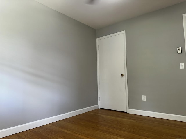 empty room with baseboards and dark wood-style floors