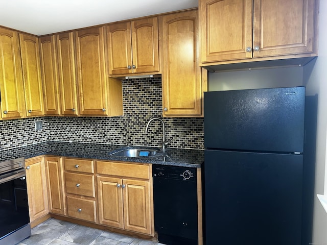 kitchen featuring black appliances, a sink, decorative backsplash, dark stone countertops, and brown cabinets