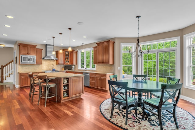 61 Governors Way, Madison, CT 06443 - kitchen with wall chimney exhaust hood, stainless steel appliances, a kitchen island, brown cabinets, and recessed lighting