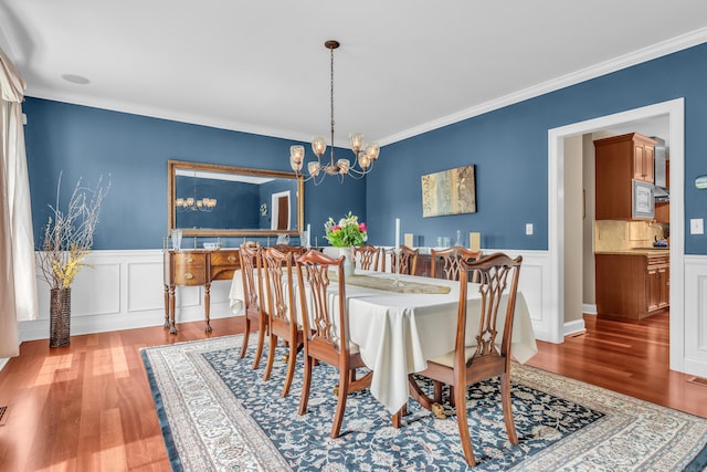 61 Governors Way, Madison, CT 06443 - dining area featuring wood finished floors, a chandelier, ornamental molding, wainscoting, and a decorative wall