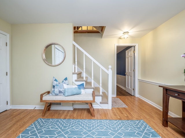 foyer entrance featuring wood finished floors, stairs, and baseboards