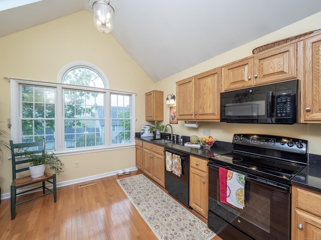 kitchen with black appliances, a sink, dark countertops, light wood-style flooring, and baseboards