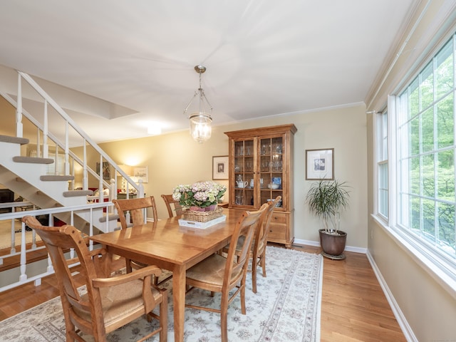 dining space featuring plenty of natural light, stairway, light wood-style flooring, baseboards, and ornamental molding
