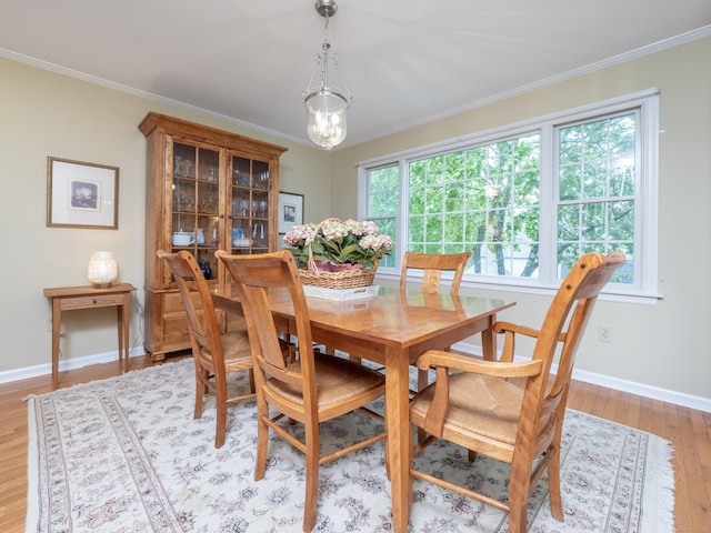 dining room with crown molding, light wood-type flooring, plenty of natural light, baseboards, and a chandelier