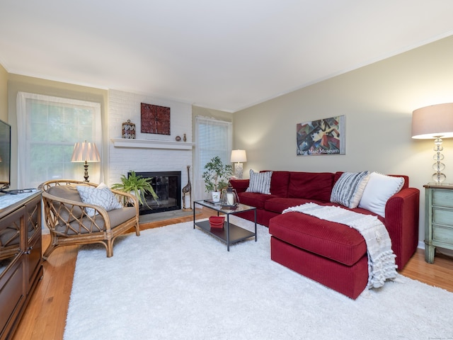 living area featuring wood finished floors, a brick fireplace, and crown molding