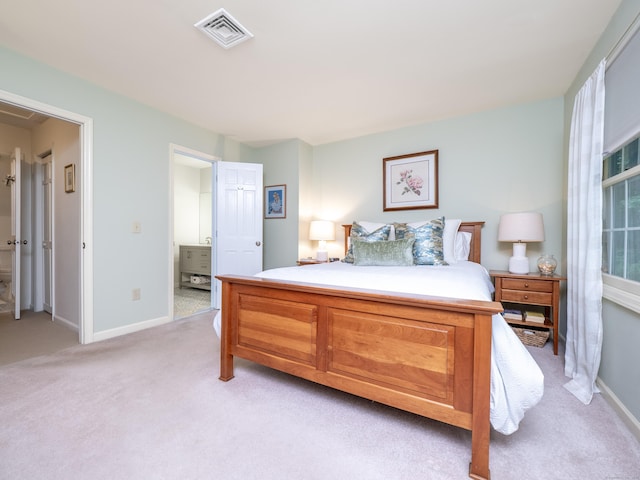 bedroom with light carpet, baseboards, and ensuite bath
