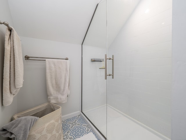 bathroom with a stall shower, vaulted ceiling, and baseboards