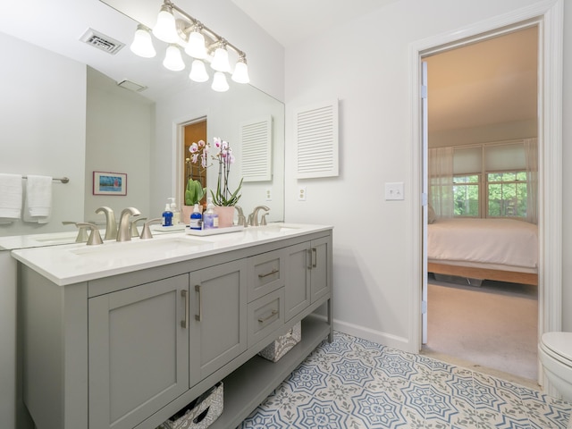 full bath featuring toilet, baseboards, double vanity, and connected bathroom