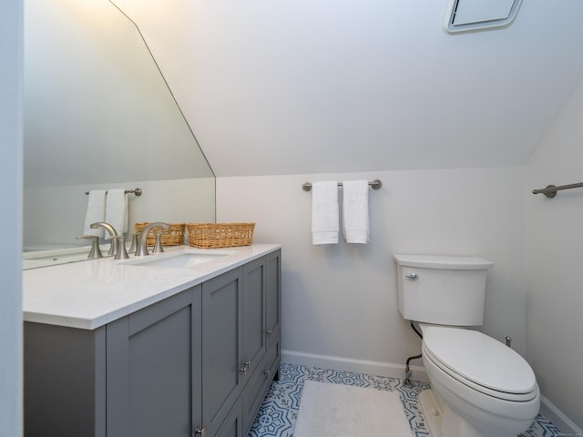bathroom with baseboards, toilet, lofted ceiling, and vanity