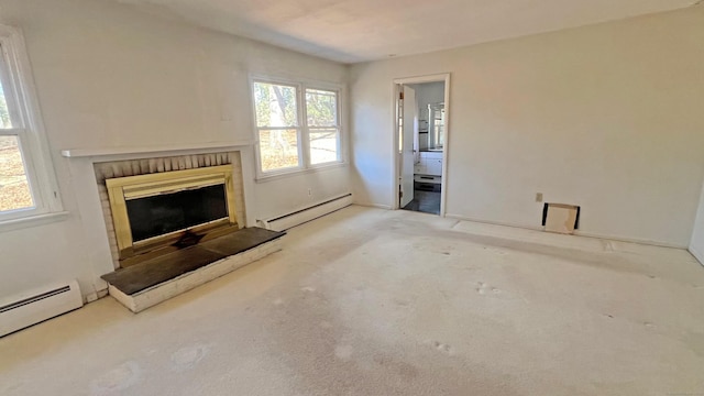 unfurnished living room with baseboard heating, plenty of natural light, a baseboard heating unit, and a fireplace