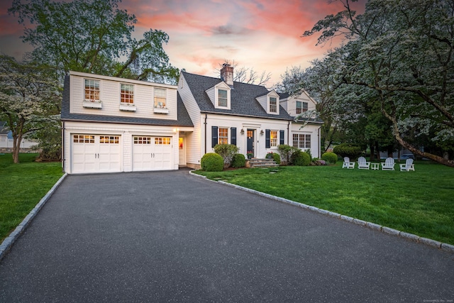 view of front of property with driveway, a yard, an attached garage, and a chimney