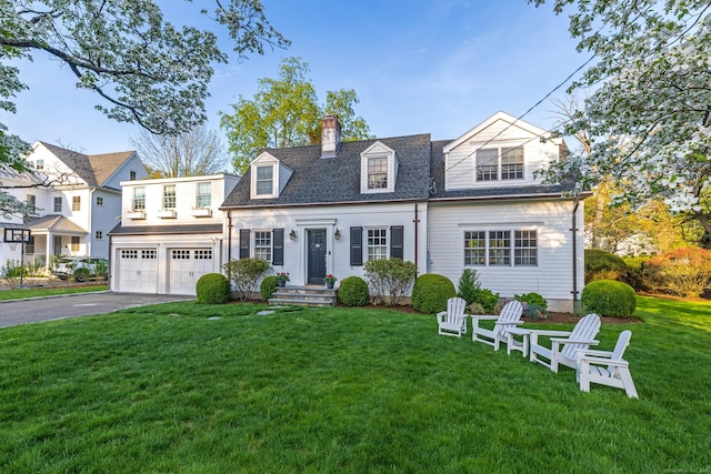 view of front of home with asphalt driveway, a chimney, a front yard, a garage, and a shingled roof