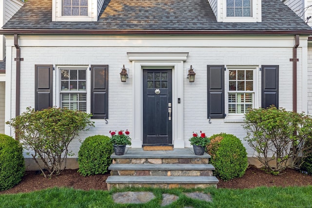 property entrance featuring brick siding and roof with shingles