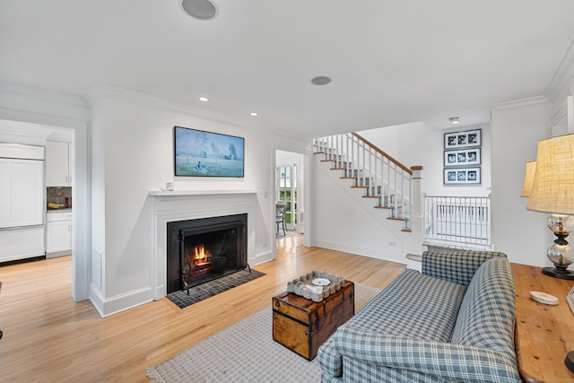 living area with ornamental molding, a fireplace with flush hearth, stairs, light wood-style flooring, and baseboards