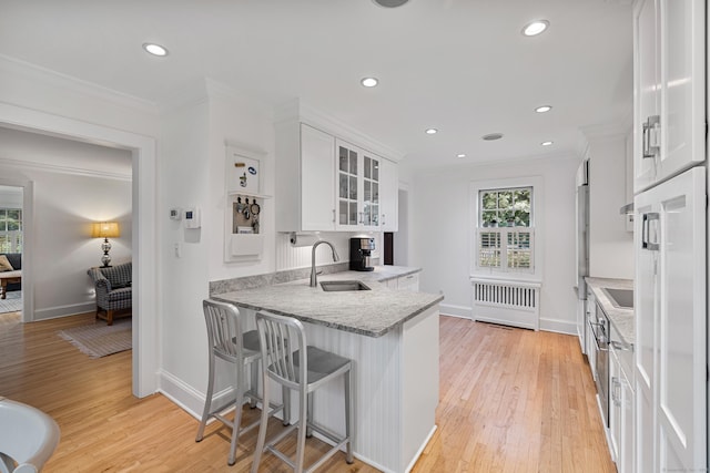kitchen featuring white cabinets, a sink, crown molding, glass insert cabinets, and recessed lighting
