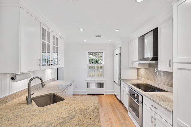kitchen featuring a sink, oven, wall chimney range hood, white cabinets, and recessed lighting